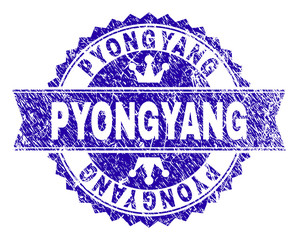 PYONGYANG rosette seal watermark with distress style. Designed with round rosette, ribbon and small crowns. Blue vector rubber watermark of PYONGYANG label with dirty texture.