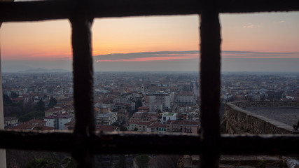 Fototapeta na wymiar Bergamo, the old town, one of the beautiful city in Italy. Sunrise from behind the metal gate of Porta San Giacomo. Panorama on the lower city