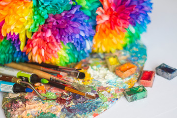 multi-colored chrysanthemums on the palette with paints and brushes of the artist