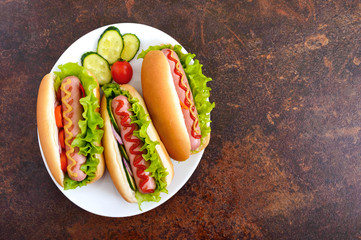 Tasty hot dogs with sausage grill, ketchup, mustard, lettuce, tomatoes on a white plate. The top view. Flat lay