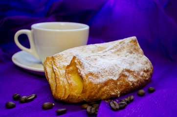 cup of coffee, grains of coffee with a bun on a purple background