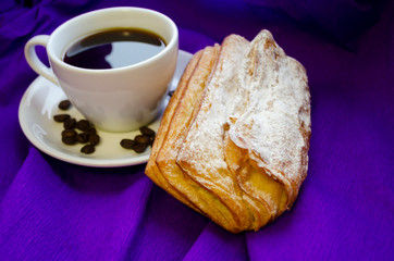 cup of coffee, grains of coffee with a bun on a purple background