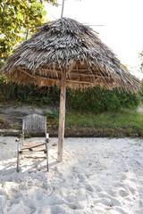 Silla y sombrilla de guano lugar de vacaciones y de relajación mirando el mar, la arena y disfrutando del sol en la playa Bomani en Tanzania, Africa del Este