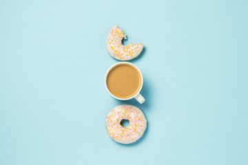 White Cup, coffee or tea with milk and fresh tasty donuts on a blue background. Bakery concept, fresh pastries, delicious breakfast, fast food. Flat lay, top view.