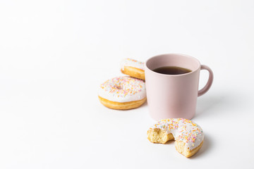 Pink Cup with coffee or tea and fresh tasty donuts, sweet multicolored decorative candy on a white background. Bakery concept, fresh pastries, delicious breakfast, fast food.