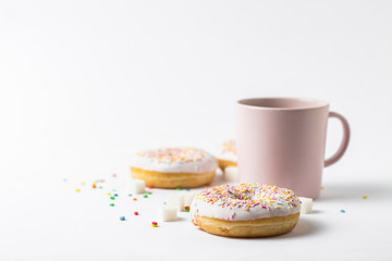 Pink Cup with coffee or tea and fresh tasty donuts, sweet multicolored decorative candy on a white background. Bakery concept, fresh pastries, delicious breakfast, fast food.
