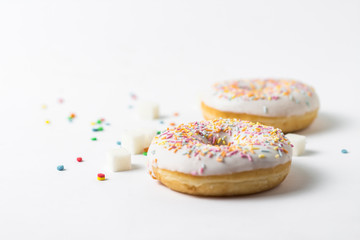 Fresh tasty donuts and sweet multicolored decorative candy on a white background. Bakery concept, fresh pastries, delicious breakfast.