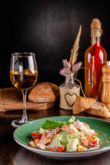 The concept of Italian cuisine. Caesar salad with salmon, lettuce mix, cherry tomatoes and parmesan cheese. A glass of white wine on the table. Serving dishes in the restaurant