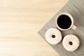 Tasty, sweet, fresh donuts and a cup with black coffee on the wooden background. Breakfast concept, fast food, coffee shop, bakery.