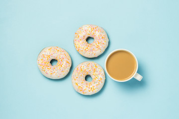 White Cup, coffee or tea with milk and fresh tasty donuts on a blue background. Bakery concept, fresh pastries, delicious breakfast, fast food. Flat lay, top view.