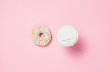 Paper cup with coffee or tea. Fresh tasty sweet donut on a pink background. Bakery concept, fresh pastries, delicious breakfast, fast food, coffee shop. Flat lay, top view.