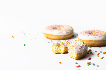 Fresh tasty donuts and sweet multicolored decorative candy on a white background. Bakery concept, fresh pastries, delicious breakfast.