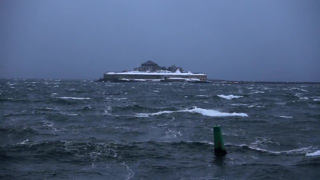 Wavy and stormy waters of Trondheimsfjorden fiord. View on Munkholmen island with big fortress, View from Trondheim shore. Middle Norway.