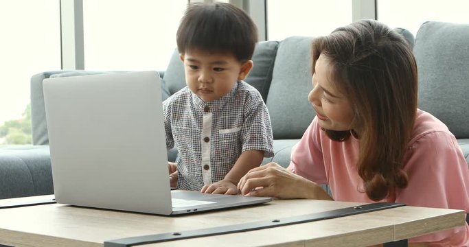Asian mother and son using notebook, then watching video , concept for Asian mother and son using notebook in living room.