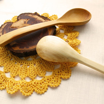 Wooden spoons on isolated background, crocheted yellow lace, napkin. The idea of healthy food, handmade, homemade food, needlework
