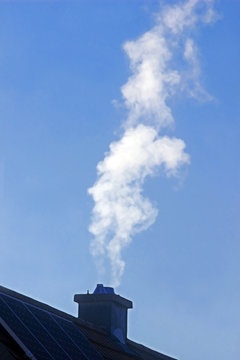 white smoke escaping from the chimney of a house