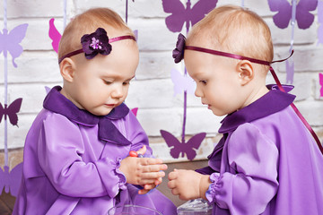Fototapeta premium One-year-old twins on the birthday. Cute twin sisters celebrating their 1th birthday. Little twins girl with candies