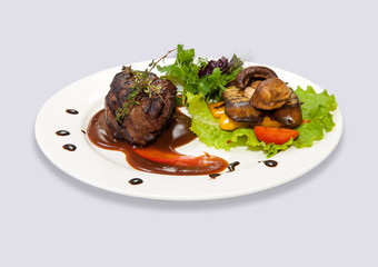 Meat in red sauce with mushrooms and herbs on a plate