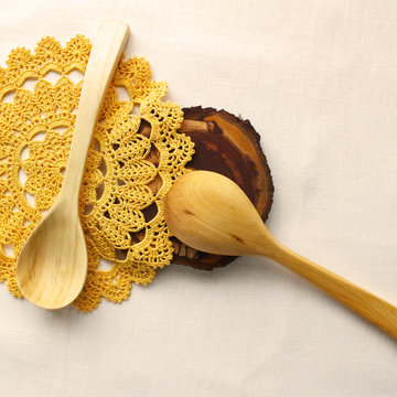 Wooden spoons on isolated background, crocheted yellow lace, napkin. The idea of healthy food, handmade, homemade food, needlework