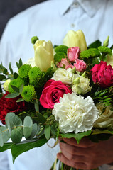 Man in a white shirt holding a bouquet of flowers