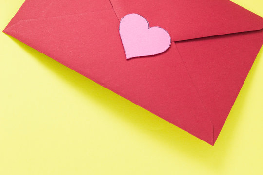 Dark red triangle envelope with large pink heart on yellow background Valentine's day or festive concept Letter or invitation inside closed envelope Minimalist concept image with free space