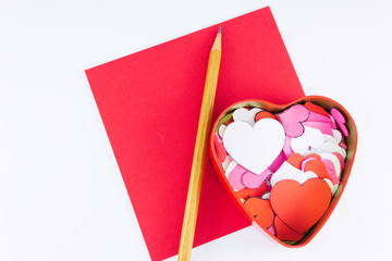 Wooden pencil on an empty red letter near to a box for valentines and different colors inside on a white background Valentine's day or festive concept Letter or invitation inside Minimalist concept