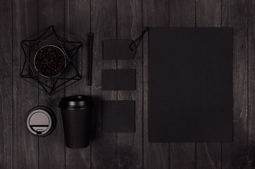 Modern elegance workplace or concept design for restaurant and coffee shop advertising - black paper cup, cap, blank paper, stationery, six-pointed star on dark wood board.