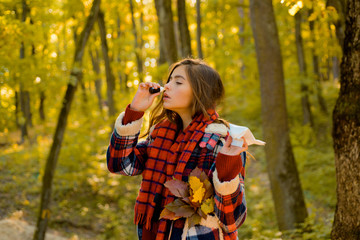 Sick girl with runny nose and fever. Woman with napkin sneezing in the yellow park. Young woman with handkerchief. Woman makes a cure for the common cold in autumn park. Healthcare.