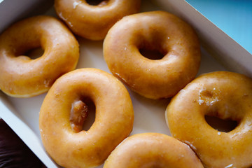 A dozen of Golden glazed Doughnuts in the box