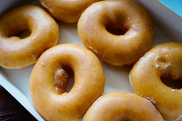 A dozen of Golden glazed Doughnuts in the box