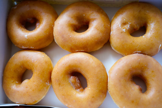 A dozen of Golden glazed Doughnuts in the box