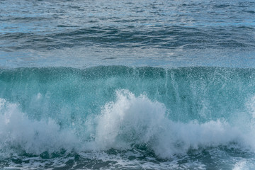 Turquoise Blue Wave Breaking and Washing into Shore in Italy