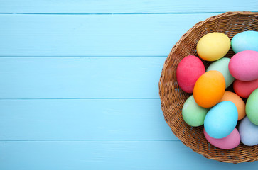 Colorful easter eggs in basket on blue background