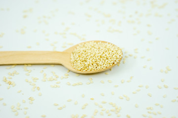 White sesame on wooden spoon isolated on white background.