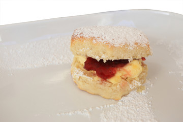 Fresh baked scones with butter and jam, top with icing on white plate.