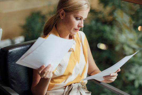 Pretty Caucasian blonde serious businesswoman reading a document.