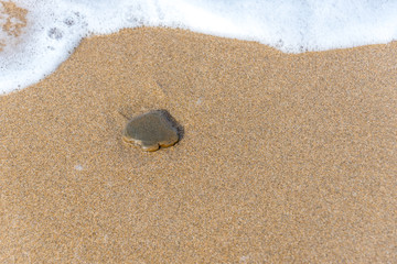 Spade Shaped Stone on a Sandy Beach with Surf