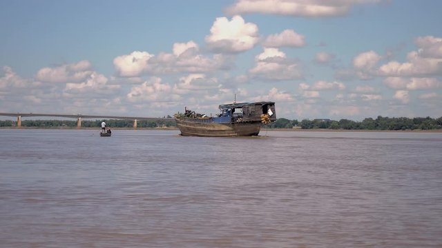 Old wooden barge on river passing by a fisher rowing small dugout canoe