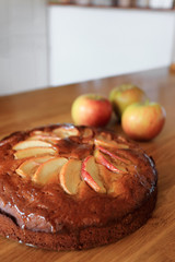 Homemade apple cake and fresh apples on wooden table.