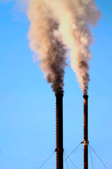 Smoke from pipes against the sky close up. Environmental pollution. Bright sun shines.