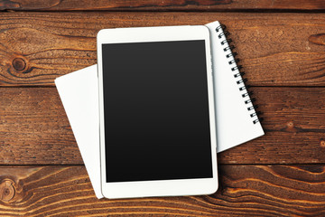 Tablet with notepad on wooden background