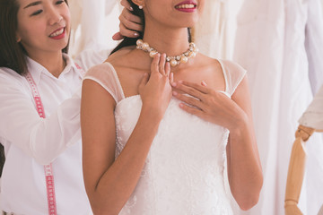Fototapeta na wymiar Bride fitting dress in atelier with wedding assistant.