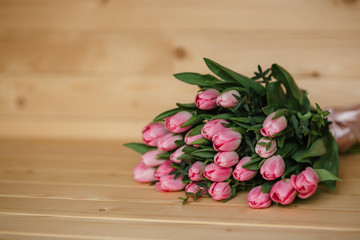 Bouquet of pink tulips with a beautiful bow on a wooden background