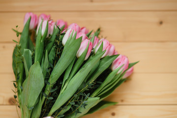 Bouquet of bright pink tulips with a beautiful bow on a wooden background