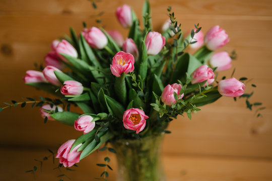 A bouquet of pink tulips in a beautiful crystal vase on wooden background. Spring