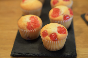 Cherry muffins on black plate for party.