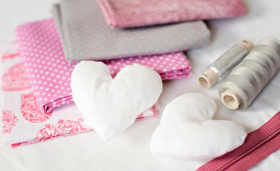 Obraz na płótnie Canvas background of white handmade textile hearts and sewing tools and accessories in pink - image