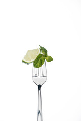slice of lime and mint leaves on fork isolated on white