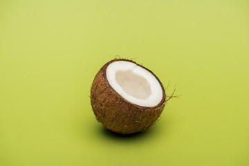 half of ripe fresh coconut on green background