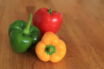 Composition with three color - red, green, yellow fresh sweet pepper or bell pepper on wooden table with copy space.
